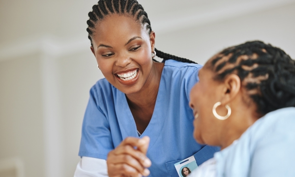 Female patient and female nurse laughing together.