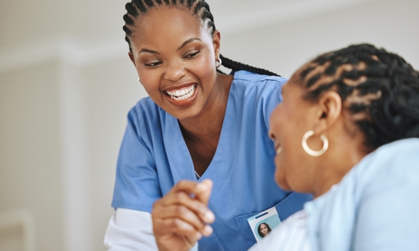 Female patient and female nurse laughing together.